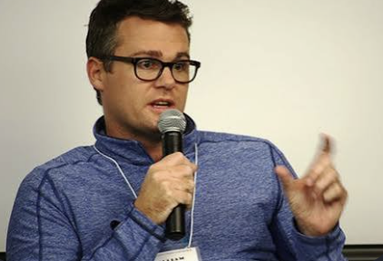 William Skelley speaking with a microphone at an event